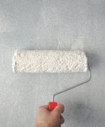 Person Holding Paint Roller On Wall