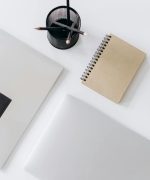 Netbook with planner and jotter placed near pencils on desk