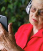 A Man in Red Shirt Using a Phone while Wearing Headphones