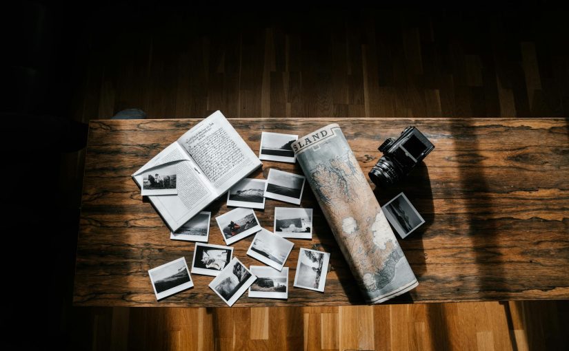 Photos and journal with map and camera on wooden table